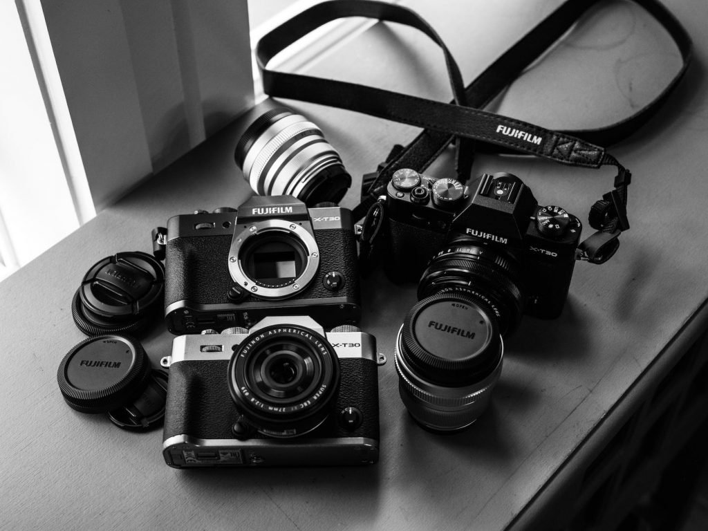 greyscale photography of three fujifilm dslr cameras